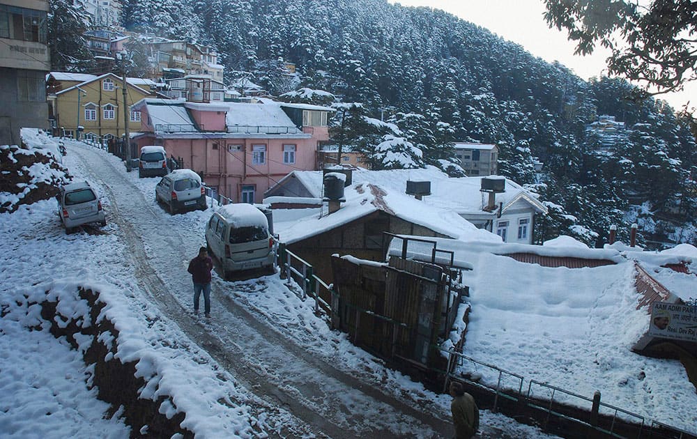 A man walks on snow covered road after heavy snowfall in Shimla.