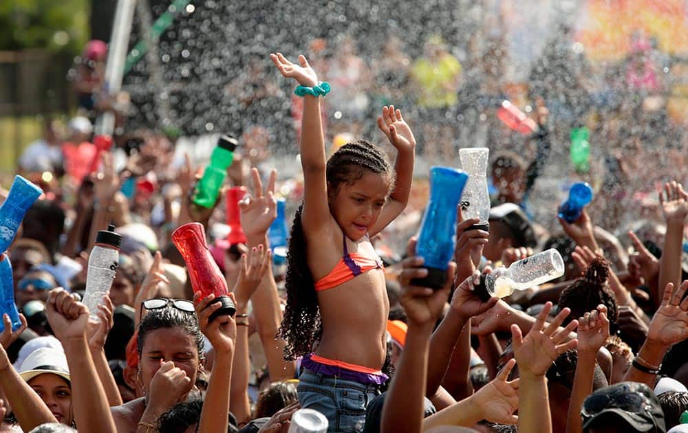 A girl raises her arms to be sprayed with water as revelers cool off on the last day of Carnival celebrations in Panama City.