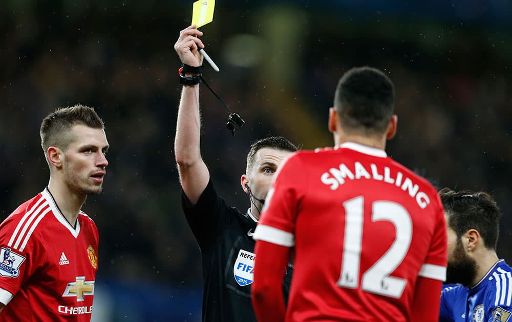 Referee Michael Oliver shows a yellow card to Manchester United's Chris Smalling during the English Premier League soccer match between Chelsea and Manchester United at Stamford Bridge stadium in London.