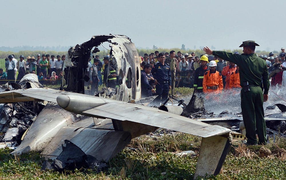 A military officer gestures by the wreckage of a Myanmar military aircraft that crashed in an area close to the airport in Naypyitaw, Myanmar.