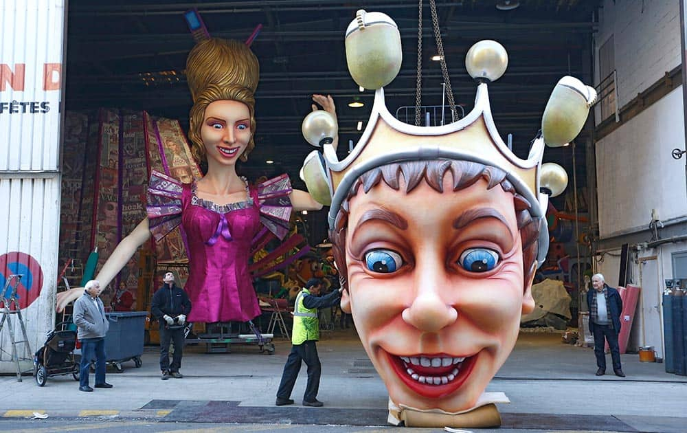 Workers set up a large mannequin figure depicting the King of the Carnival in front of the Queen of Carnival. left, during preparations for the 132th Nice carnival parade.