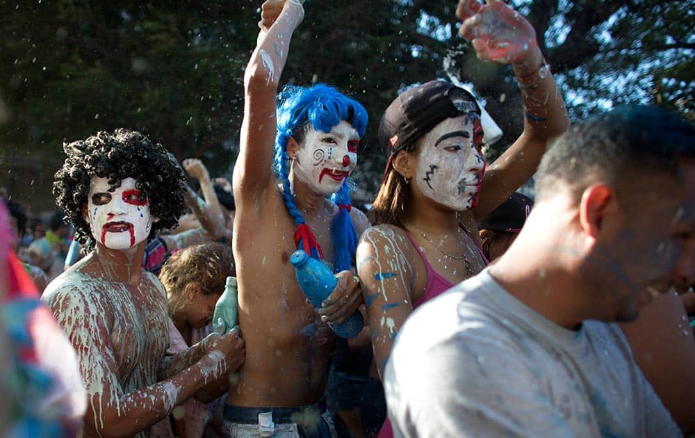 Revelers with painted faces dance as they take part in a traditional carnival ceremony, 'The Burial of the Sardine,' in Naiguata, Venezuela.