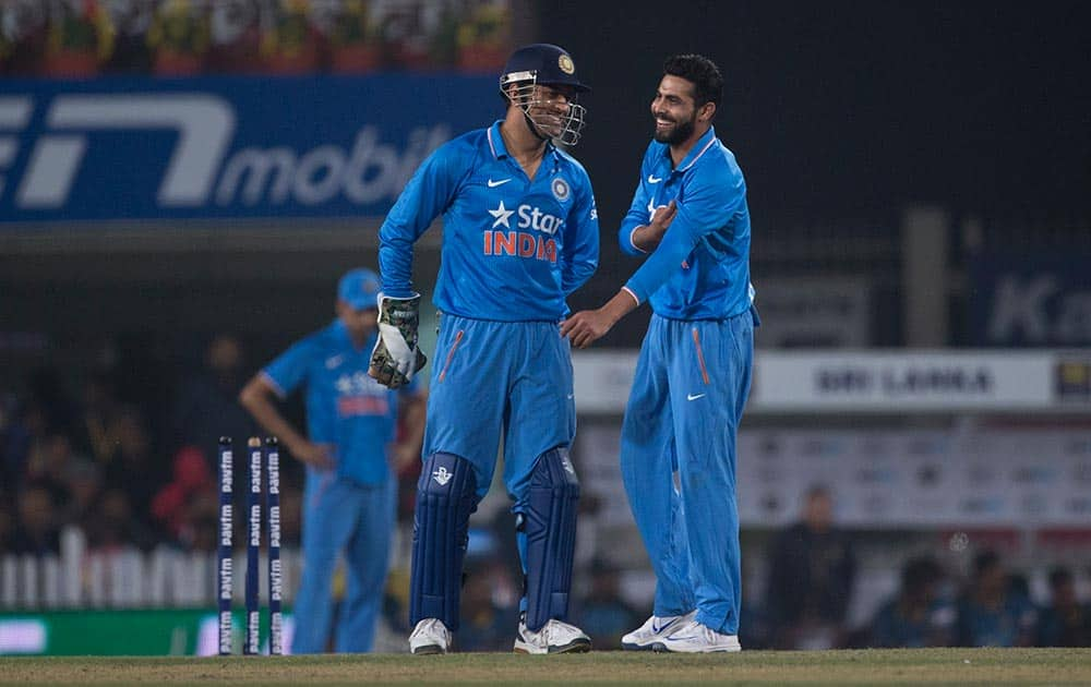 Cricketers Mahendra Singh Dhoni, left, and Ravindra Jadeja share a light moment as they wait for a third umpire's decision against Sri Lanka during the second T20 match of a three match series between the two countries, in Ranchi.