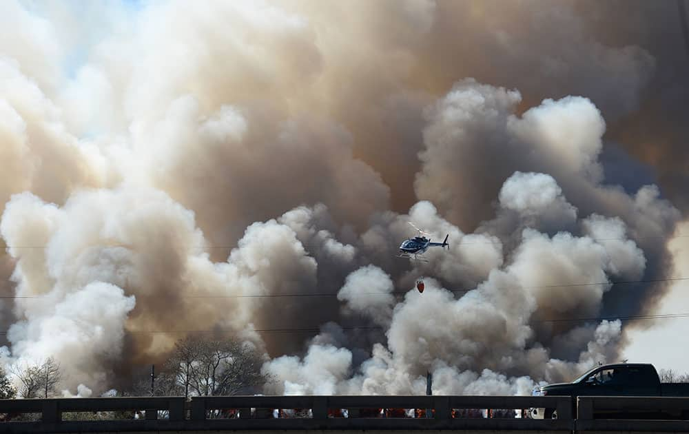 A helicopter flies past plumes of smoke during firefighting efforts on a train trestle parallel to Interstate 10 near the Bonnet Carre Spillway, west of New Orleans.