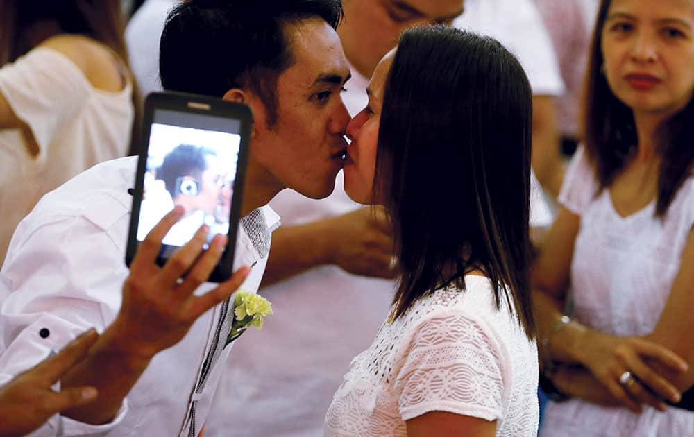 A Filipino couple takes a selfie while kissing during a mass wedding ahead of Sunday's Valentine's Day celebration in Manila, Philippines.