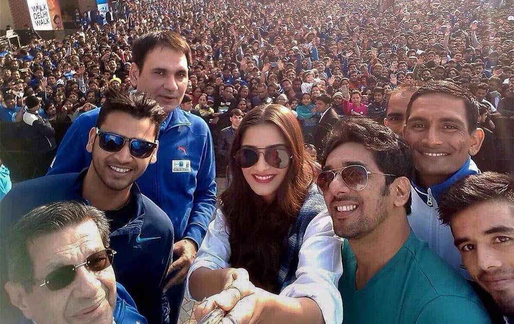 Bollywood actress Sonam Kapoor with Indian Olympians taking selfie before flagging off walk for heath initiative in New Delhi.