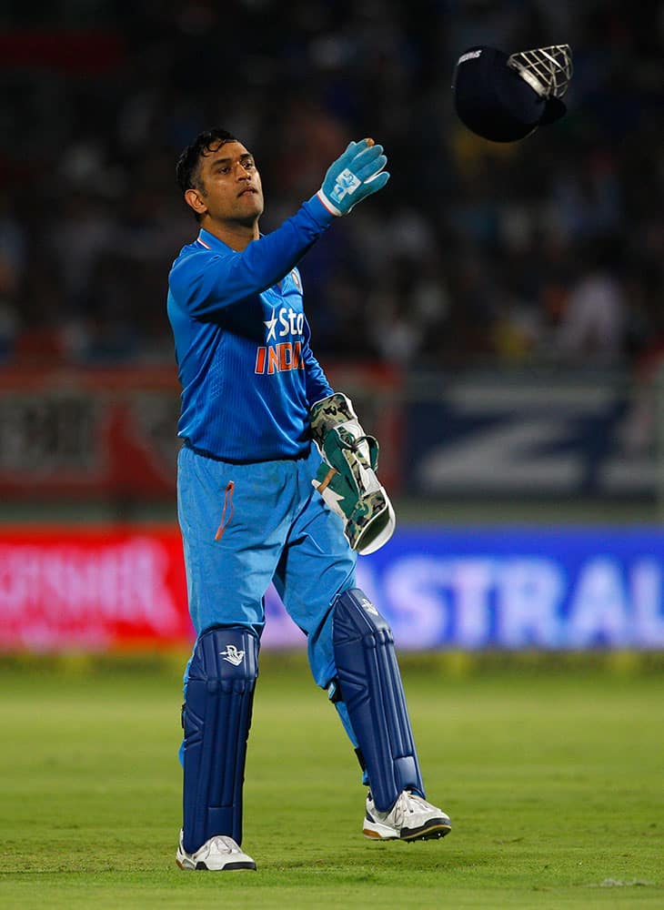 India's captain Mahendra Singh Dhoni tosses his helmet to a teammate during their third Twenty20 cricket match against Sri Lanka, in Vishakapatnam.