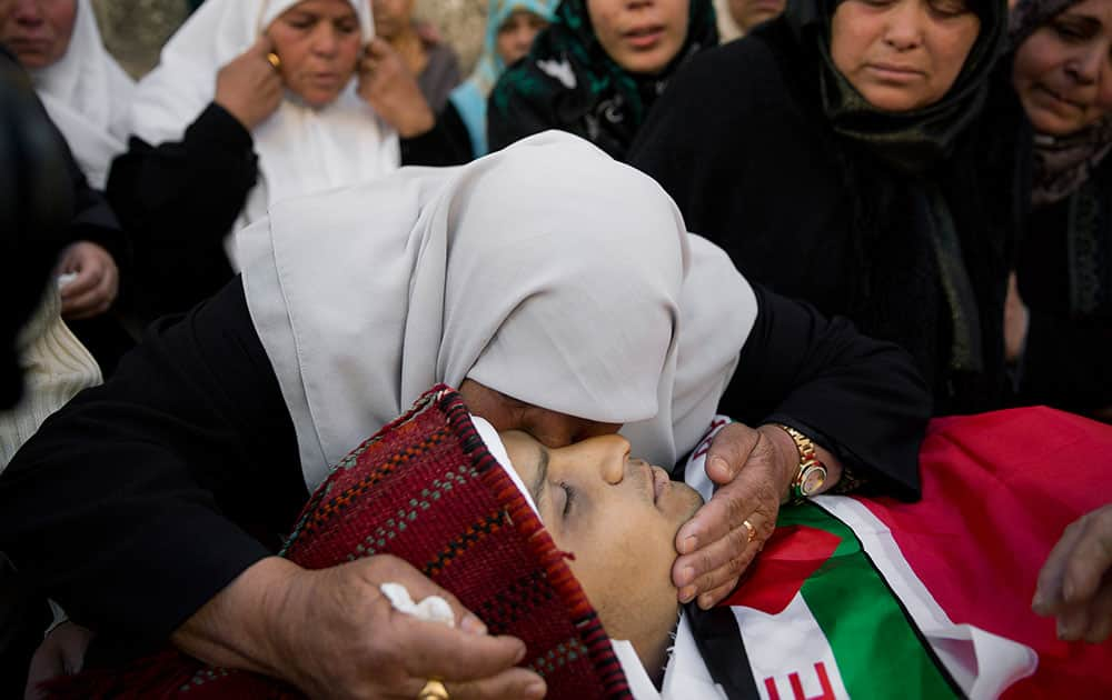 A woman kisses Naim Safi, 17, who was shot dead by Israeli forces last Sunday, during his funeral in the West Bank village of Abadiya, Bethlehem.