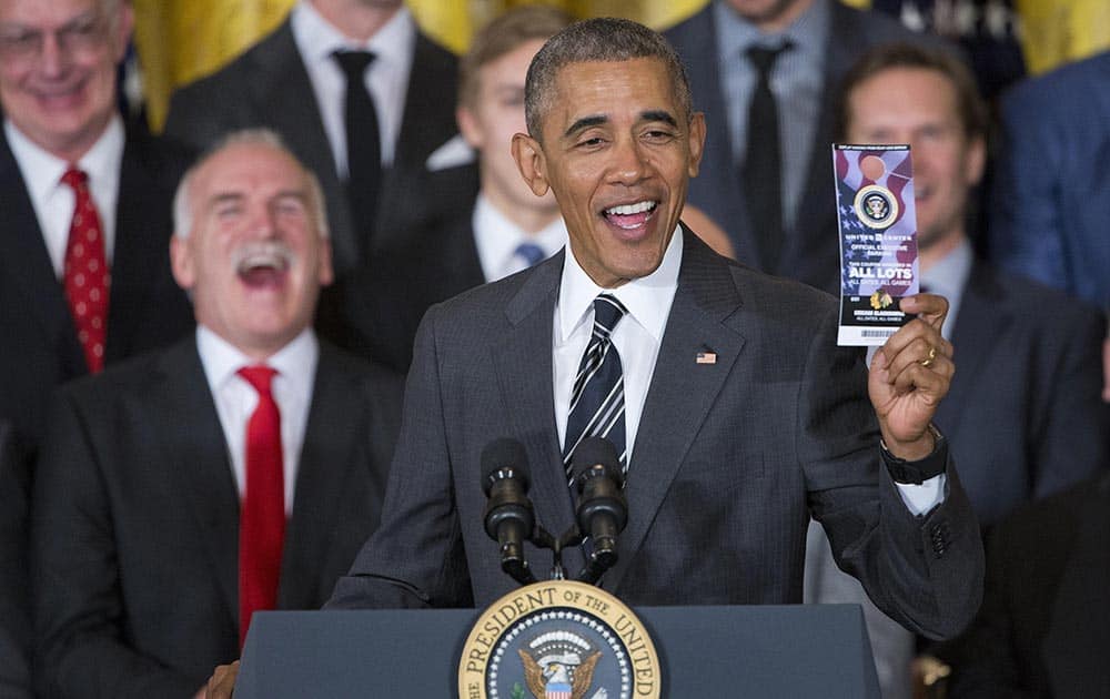 President Barack Obama holds up a parking pass that was presented to him during a ceremony to honor the 2015 NHL Stanley Cup Champion Chicago Blackhawks in the East Room of the White House in Washington.