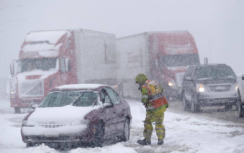 A worker gets ready to install chains on a car, at the California-Nevada border near Truckee, Calif.