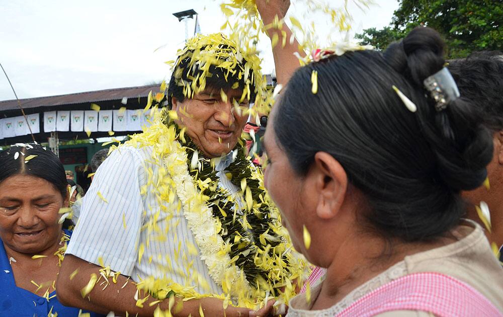 A coca farmer welcomes Bolivias President Evo Morales, center, as he arrives to a polling station to vote in Villa 14 de Septiembre, in the Chapare region, Bolivia.