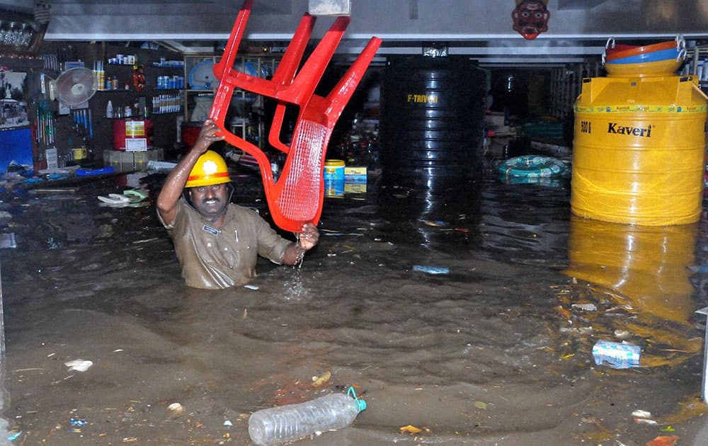 A fire brigade person carrying the things out from a shop during the Unseasonal heavy rain at Chikmagalur in Karnataka.