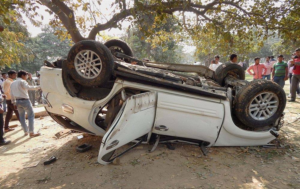 People gather near a car that overturned in Gurgaon.