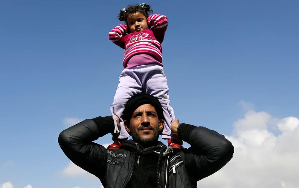 A man holds up a girl as Syrian refugees demand to open the border during a protest at the Athens' port of Piraeus.