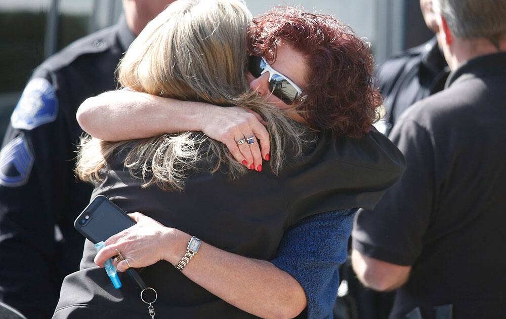 Jacki Kelley, left, director of Public Affairs for the Jefferson County, Colo., Sheriff's Department, hugs June Wegener, wife of Park County Sheriff Fred Wegener, after a motorcade passed carrying the body of Cpl. 