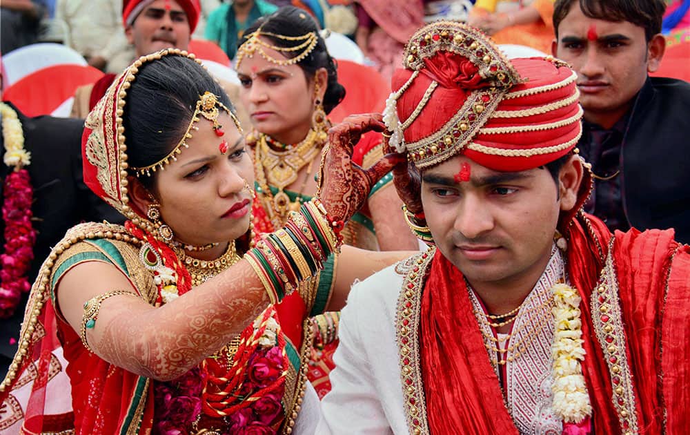 A bride adjusting the turban of groom during the patel community mass marrige function in Ahmedabad.