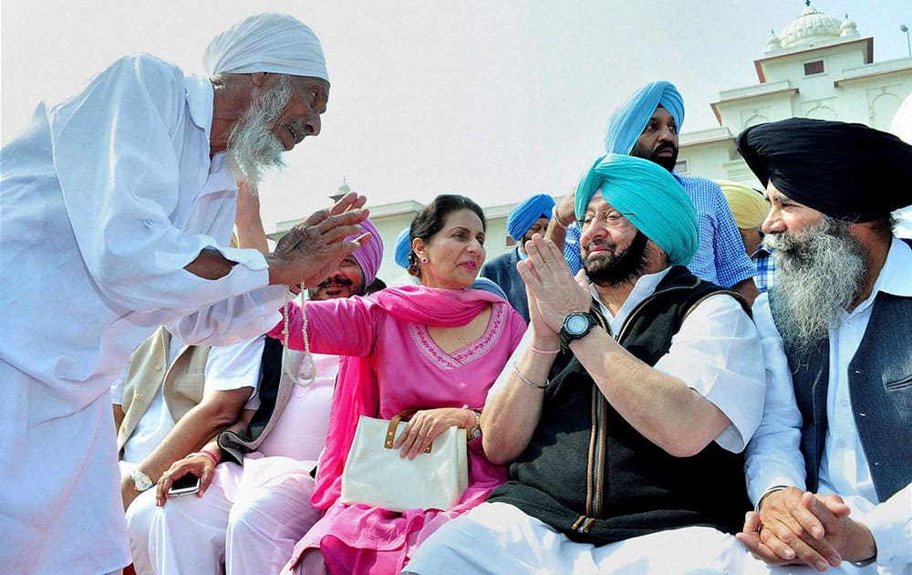PPCC Chief Capt Amarinder Singh exchanges greetings with an elderly party worker as his wife and party leader Preneet Kaur looks on during a party meeting in Patiala.