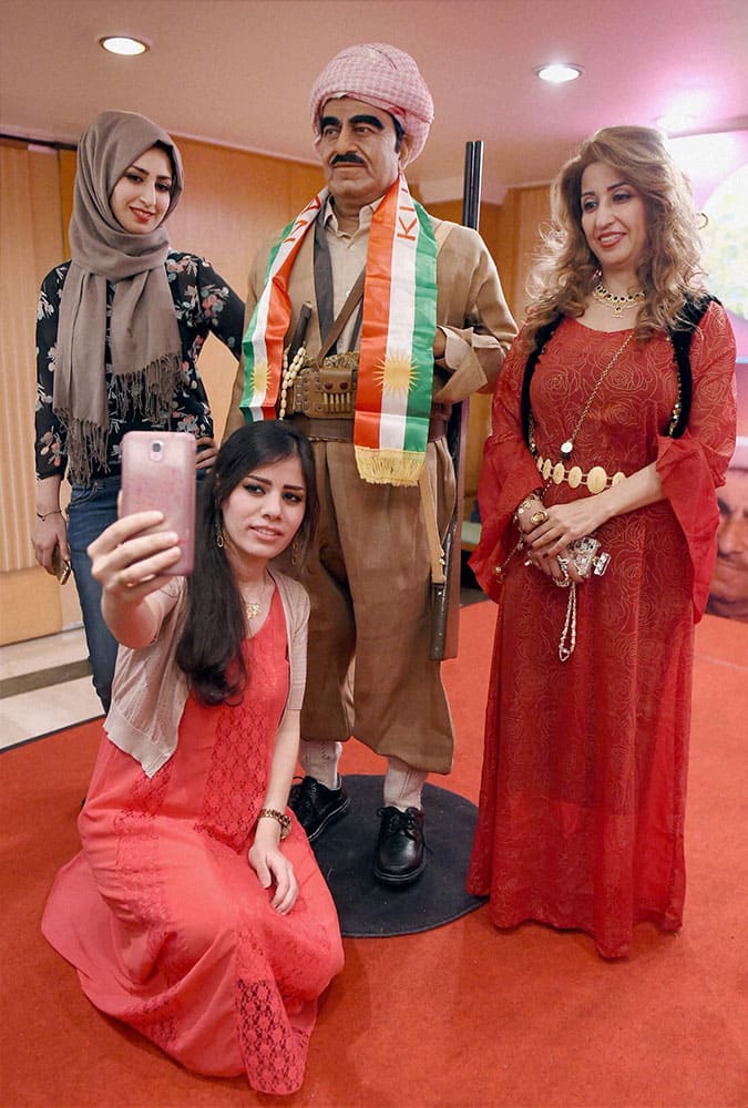 Iraqi women take a selfie with the wax model of Mustafa Barzani, revolutionary leader of Kurdistan-Iraq sculpted by Sunil Kandalloor (unseen) in Mumbai.