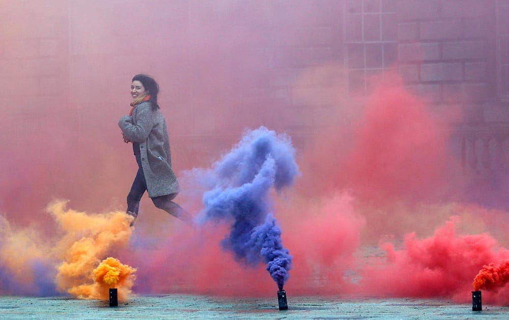 A woman runs through an artwork created by artist Filippo Minelli, a new work in his series Silence/Shapes, for the piece he let off colourful smoke bombs in Somerset House’s courtyard, in London.