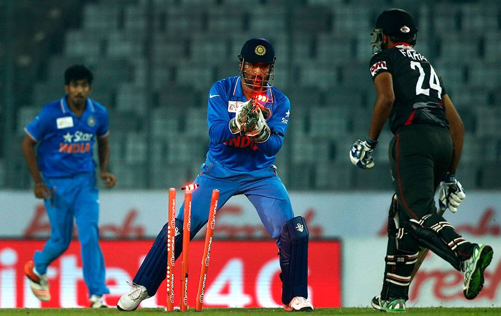 Mahendra Dhoni, center, takes the wicket of United Arab Emirates’ Farhan Ahmed, right, during the Asia Cup Twenty20 international cricket match between them in Dhaka.