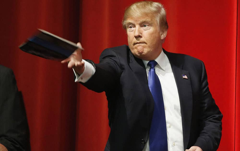 Republican presidential candidate Donald Trump tosses back something he autographed to a supporter after a campaign stop, in Wichita, Kan.