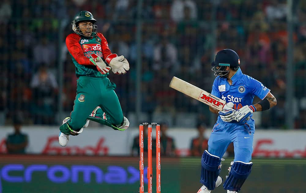 India’s Virat Kohli, right, plays a shot, as Bangladesh’s wicketkeeper Mushfiqur Rahim jumps during the Asia Cup Twenty20 international cricket final match between them in Dhaka, Bangladesh.