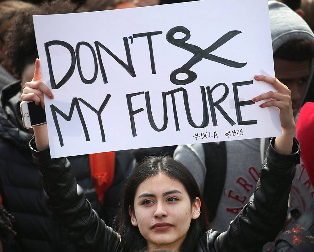 A student holds up a sign in protest as she gathers with thousands of other Boston public school students on the Boston Common, across from the Statehouse, in Boston. 