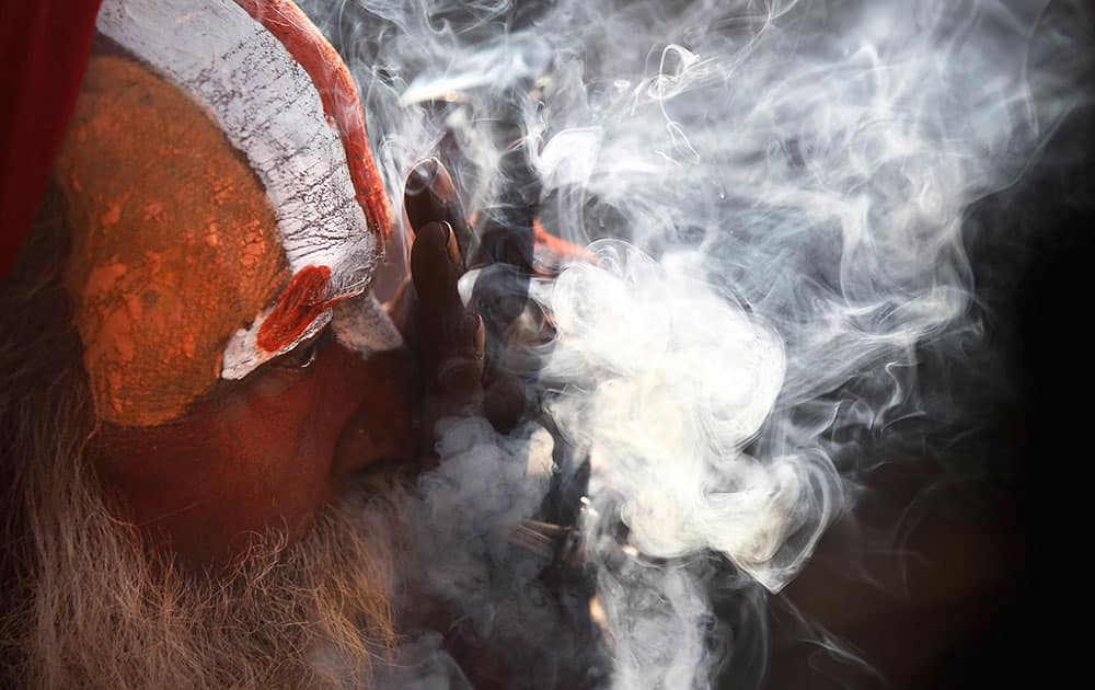 A Hindu holy man smokes marijuana at the courtyard of the Pashupatinath temple during 