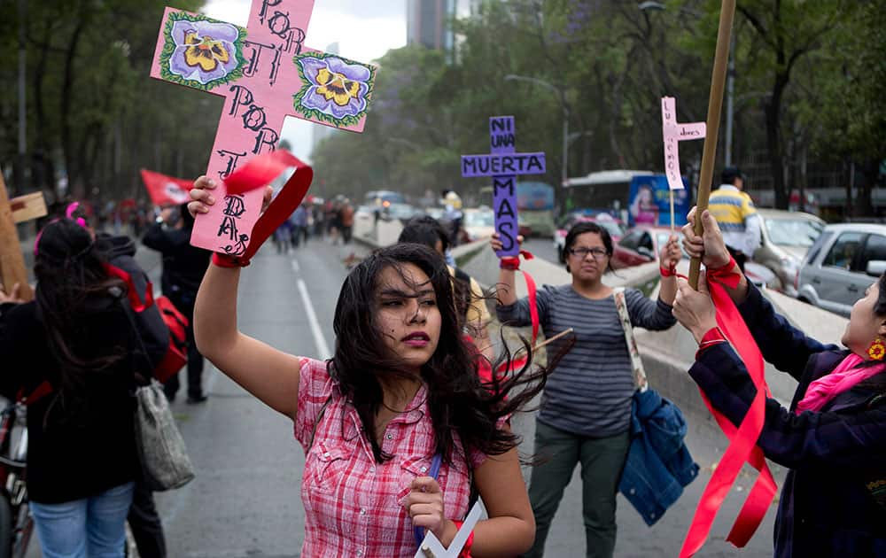 A woman carries a cross that reads in Spanish 