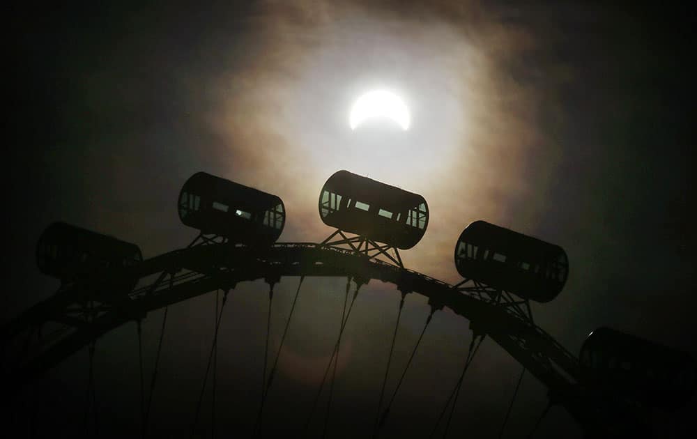 A partial solar eclipse is seen behind passenger capsules of the Singapore Flyer in Singapore. 