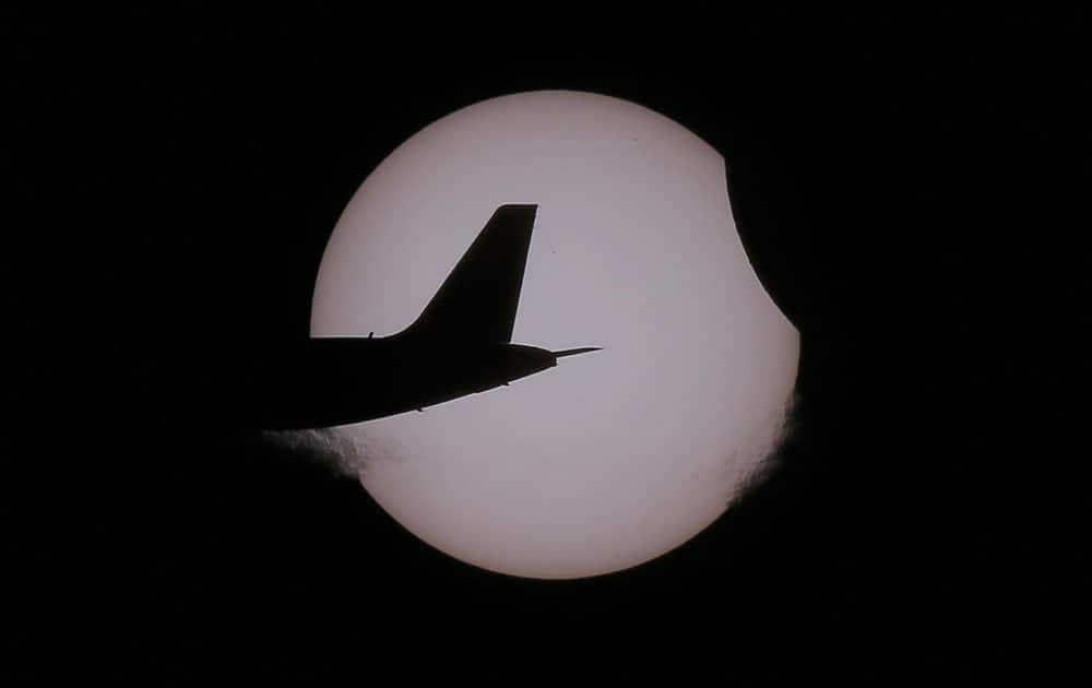 An Air Asia passenger plane flies as a partial solar eclipse occurs as seen from Taguig city, east of Manila, Philippines.