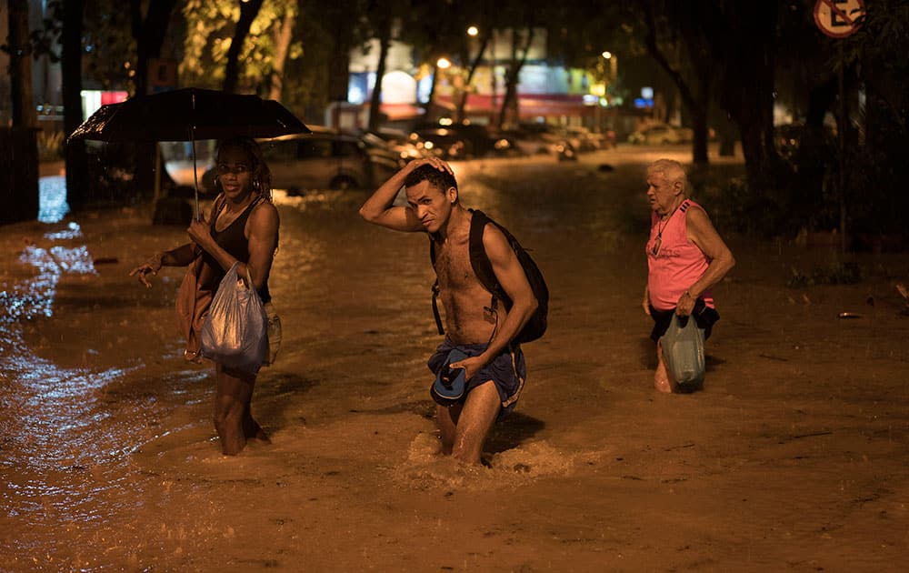 People wade through a flooded street at the Gavea neighborhood after heavy rains in Rio de Janeiro, Brazil.