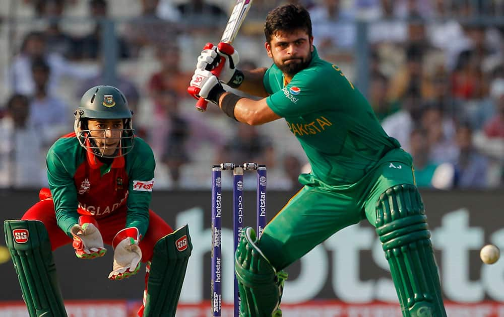 Pakistan's Ahmed Shehzad plays a shot as Bangladesh's Mushfiqur Rahim watches during their ICC World Twenty20 2016 cricket match in Kolkata.