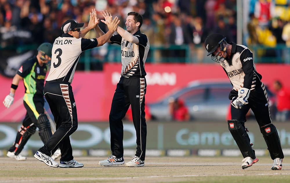 New Zealand's Mitchell Santner is congratulated by teammate's Ross Taylor and Luke Ronchi after the dismissal of Australia's David Warner during heir ICC World Twenty20 2016 cricket match at the Himachal Pradesh Cricket Association (HPCA) stadium in Dharamsala.