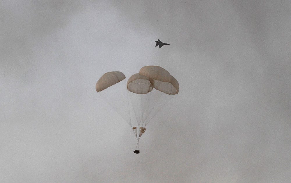 Air force aircraft flies past as a vehicle is dropped by parachute during exercise 'Iron Fist' at Pokhran.