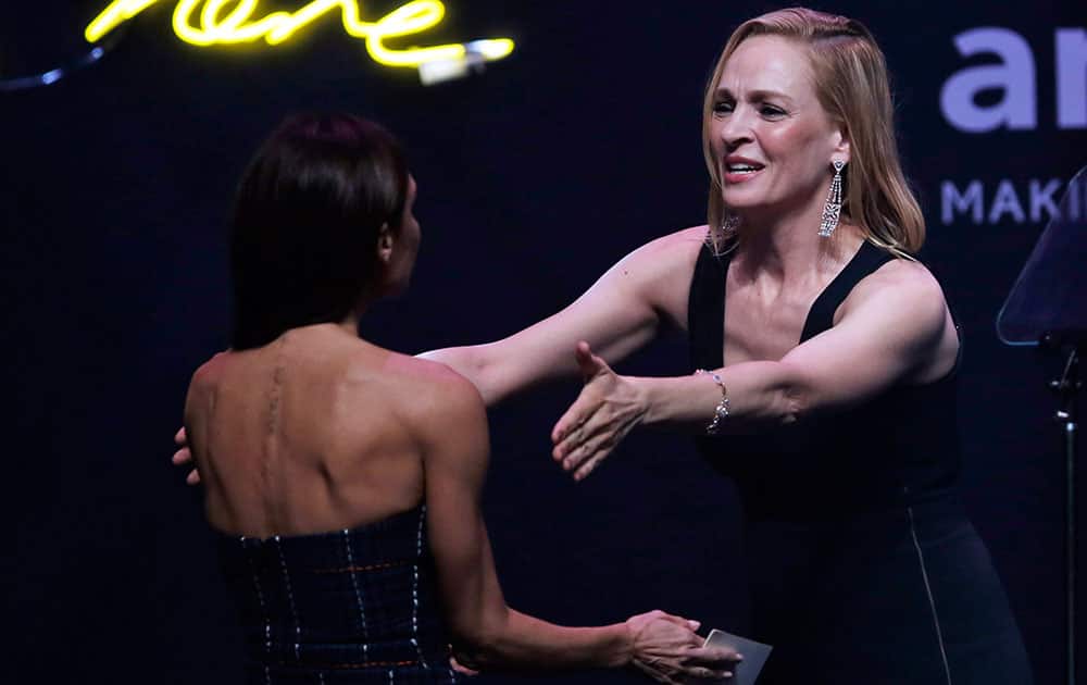U.S. actress Uma Thurman, right, greets British Fashion Designer Victoria Beckham on the stage during the fundraising gala organized by amfAR (The Foundation for AIDS Research) in Hong Kong.