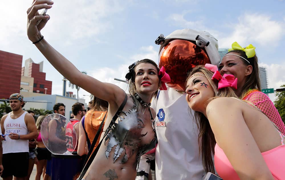 Michelle Talayer, 32, of Delray Beach, Fla., left, takes a group photograph with friends as she waits in line to attend the Ultra Music Festival.