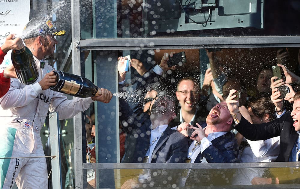 Mercedes driver Lewis Hamilton of Britain, left, sprays champagne on fans after the Australian Formula One Grand Prix at Albert Park in Melbourne, Australia.