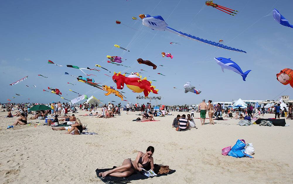A woman enjoys the sun as hundreds of kites from around the world fly through the sky at the Jumeirah beach during an international kite festival in Dubai.