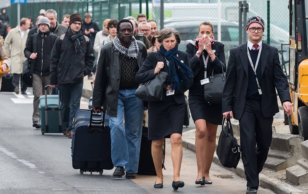 People react as they walk away from Brussels airport after explosions rocked the facility in Brussels, Belgium.
