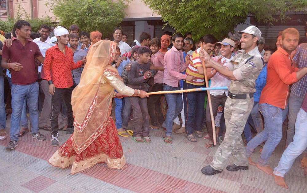 Woman beating Police personnel with stick during Lathmaar Holi celebration at Sri Krishna Janamsthan Temple.