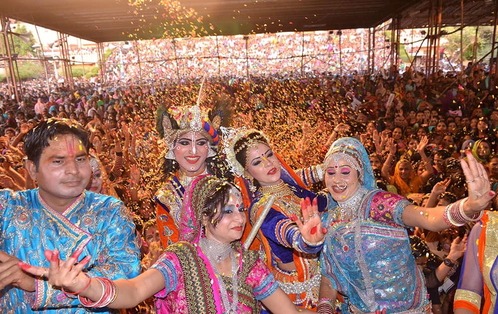 Artists dressed up as Lord Radha-Krishna, playing holi with flower petals during Latthmaar Holi celebration.