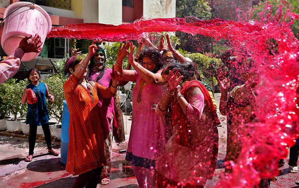 A man pours a bucket of colored water on others during Holi celebrations in Allahabad.