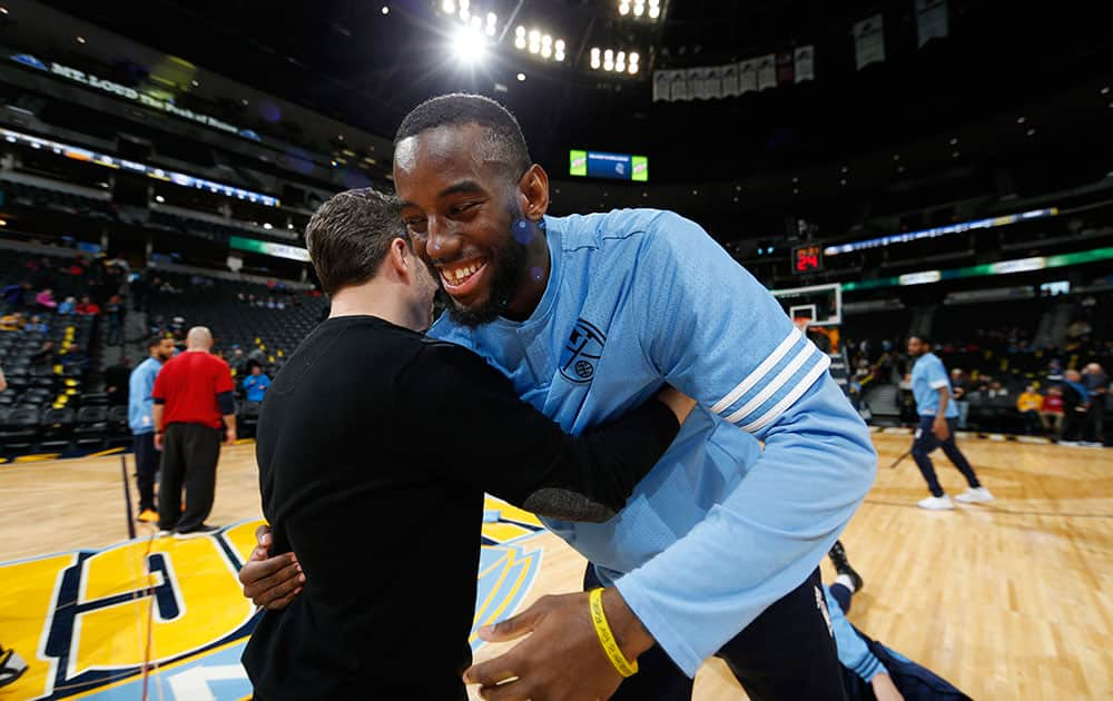 Denver Nuggets guard JaKarr Sampson, right, hugs a trainer for the Philadelphia 76ers as the teams warm up for the first half of an NBA basketball game.