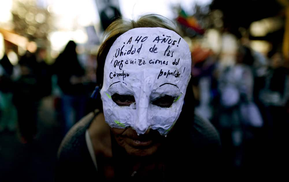 A demonstrator wears a mask that reads in Spanish: 