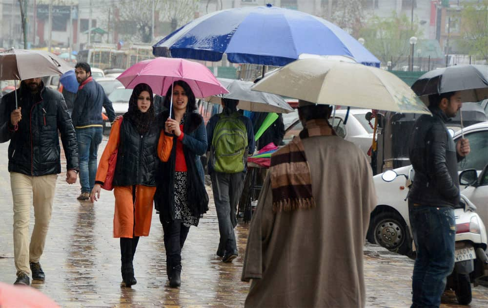 People walk under umberallas to protect themselves during incessant rains at Lal Chowk in Srinagar.