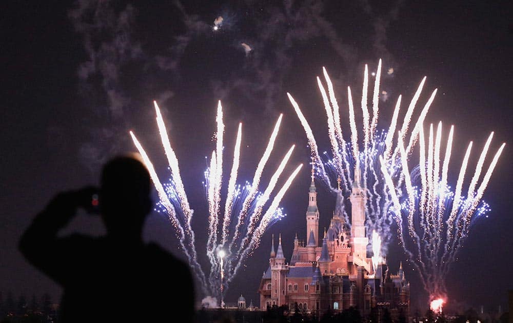 A man uses his mobile to film fireworks near the Enchanted Storybook Castle at the Shanghai Disney Resort in Shanghai.