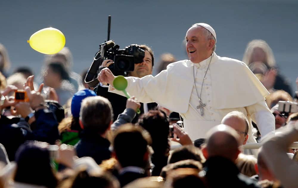 Pope Francis tries to reach for a flying balloon as he arrives with his popemobile in St. Peter's Square to attend his weekly general audience at the Vatican.
