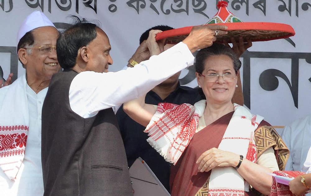Congress president Sonia Gandhi being felicitated with a traditional Assamese japi (hat), gamocha and sarai by Congress candidate from Biswanath Assembly constituency Nurjamal Sarkar while Assam Chief Minister Tarun Gogoi (L) looks on at an election rally at Biswanath Chariali in Sonitpur district, Assam.