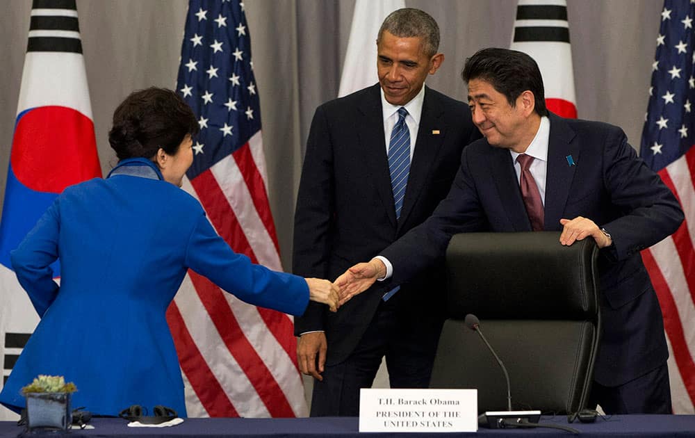 South Korean President Park Geun-hye, left, shakes hands with Japanese Prime Minister Shinzo Abe as President Barack Obama watches after their meeting at the Nuclear Security Summit in Washington.
